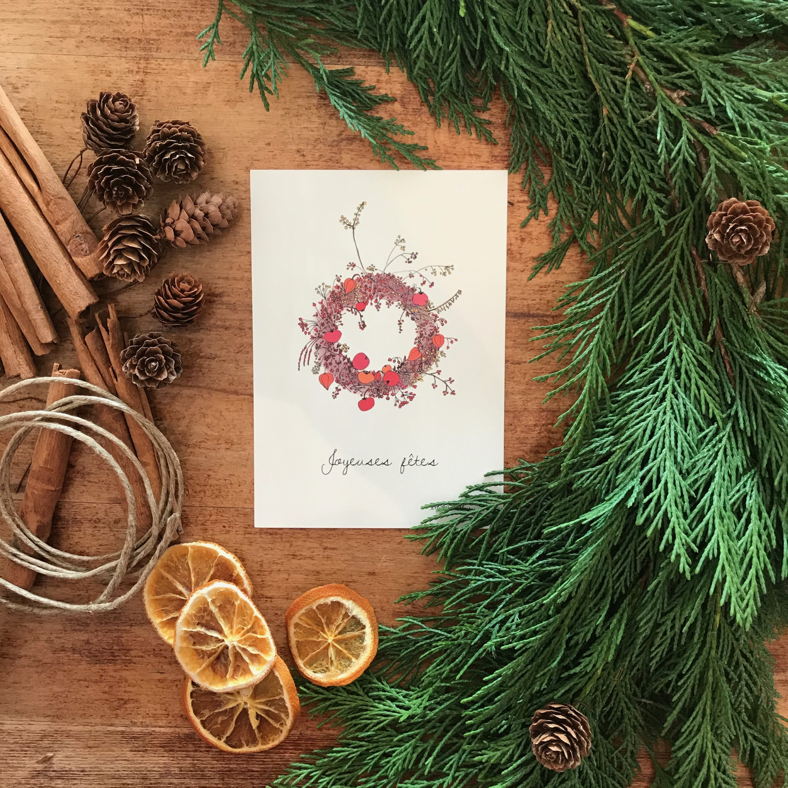 Photographie d'une carte de noël composée d'une couronne de noël et d'un texte "Joyeux Noël "